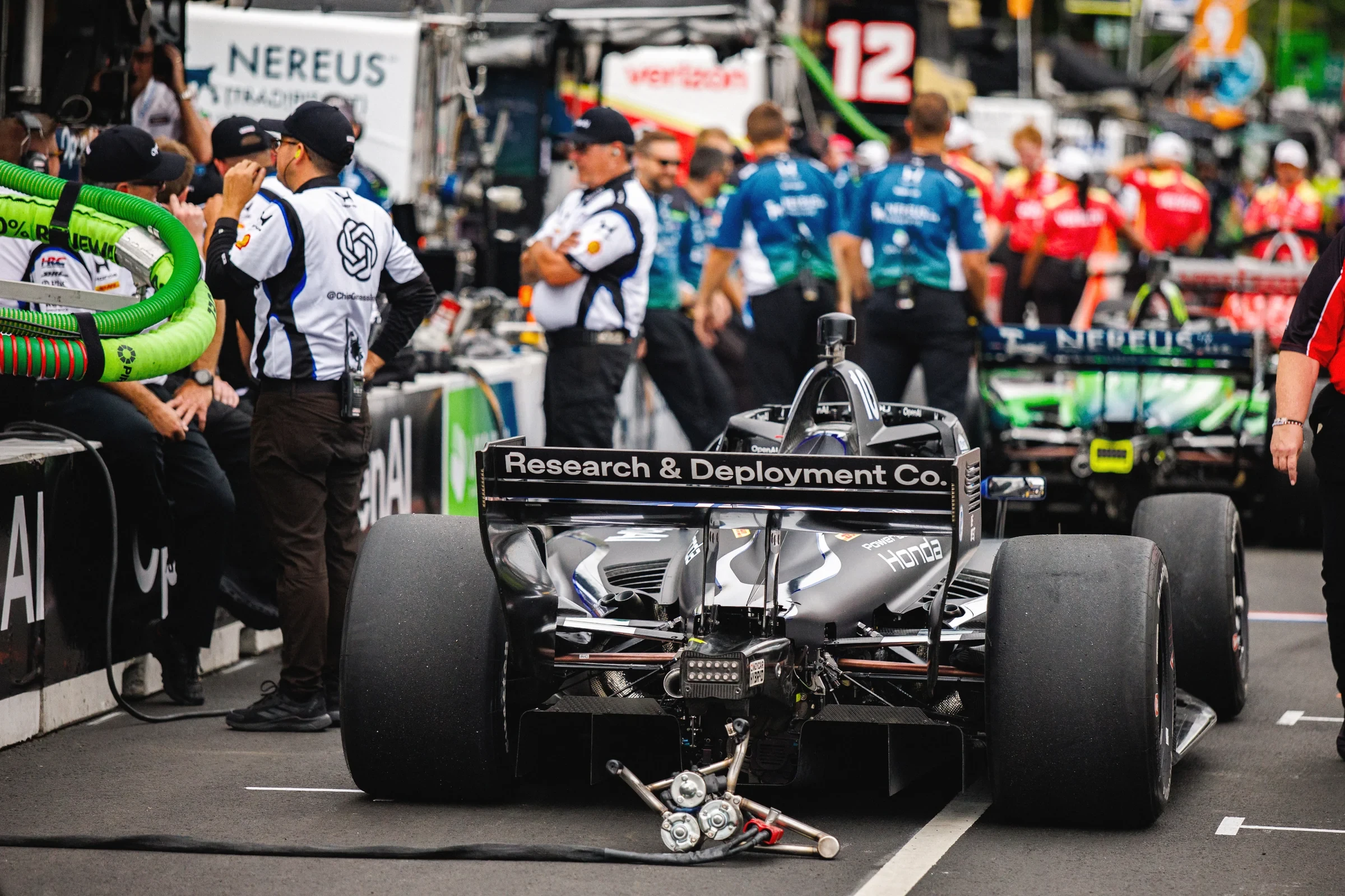 Rear view of the number 10 IndyCar surrounded by the pit crew.