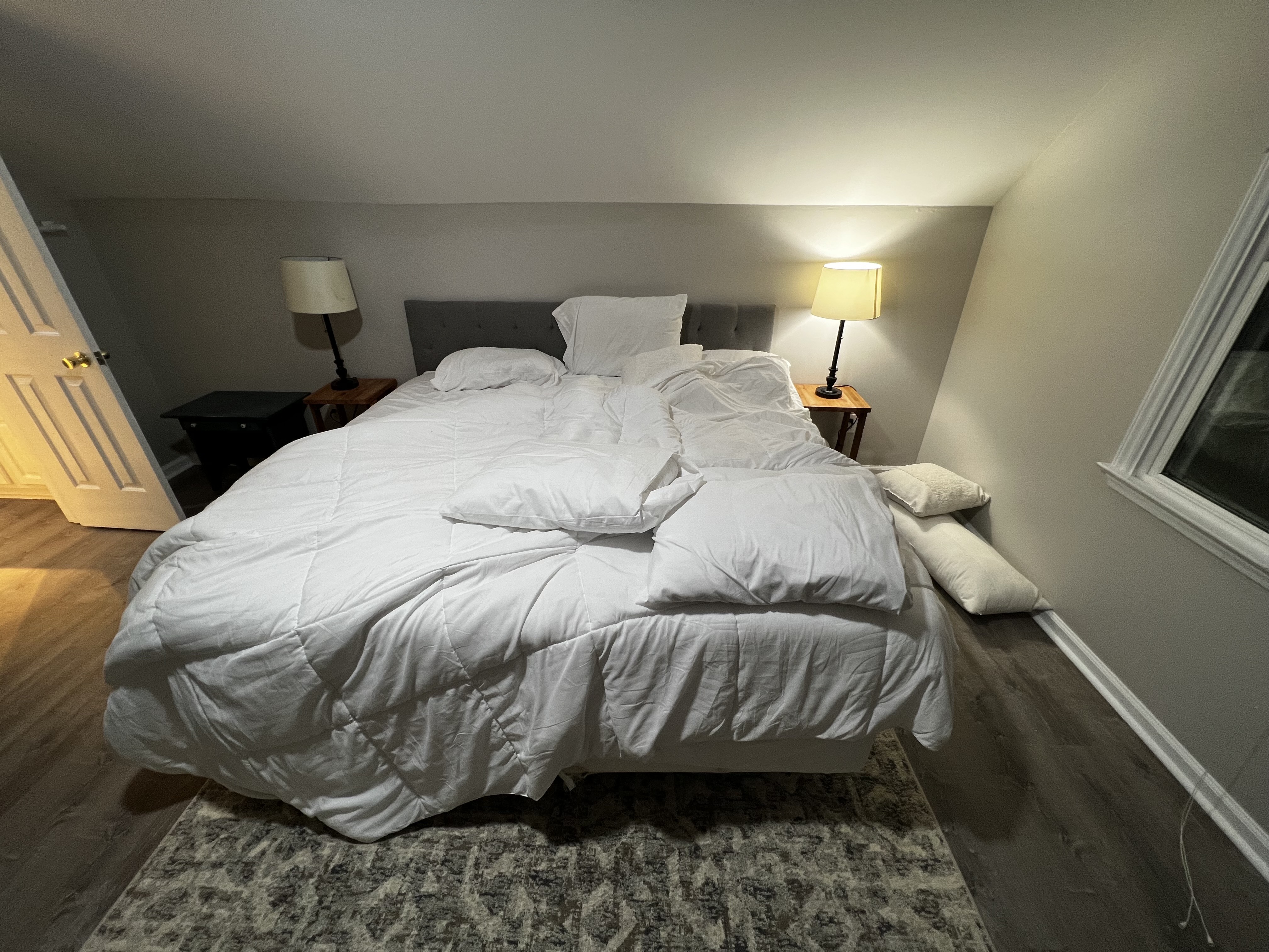 Bedroom with an unmade bed and scattered pillows