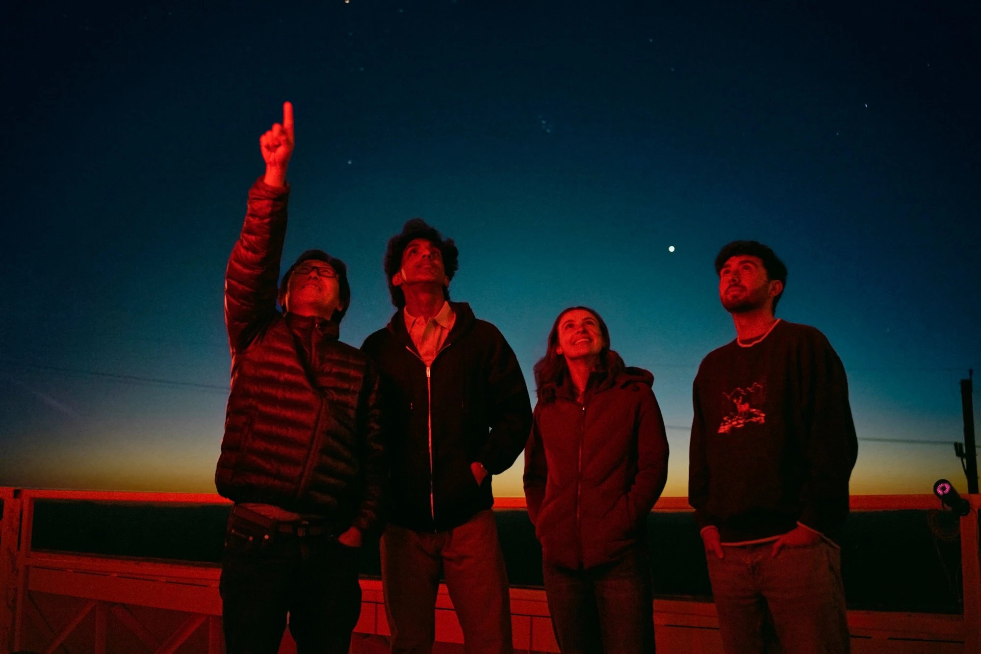 CK Chan stands with Ram, Nayera, and Hayden under red observatory light.