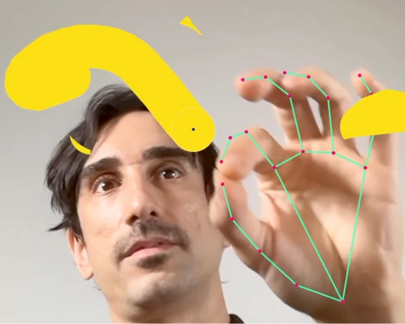 A person looking toward the camera while raising one hand, with colored dots and lines overlaid on the fingers to illustrate hand-tracking. Bright yellow drawn shapes appear around the hand and face on a neutral background.
