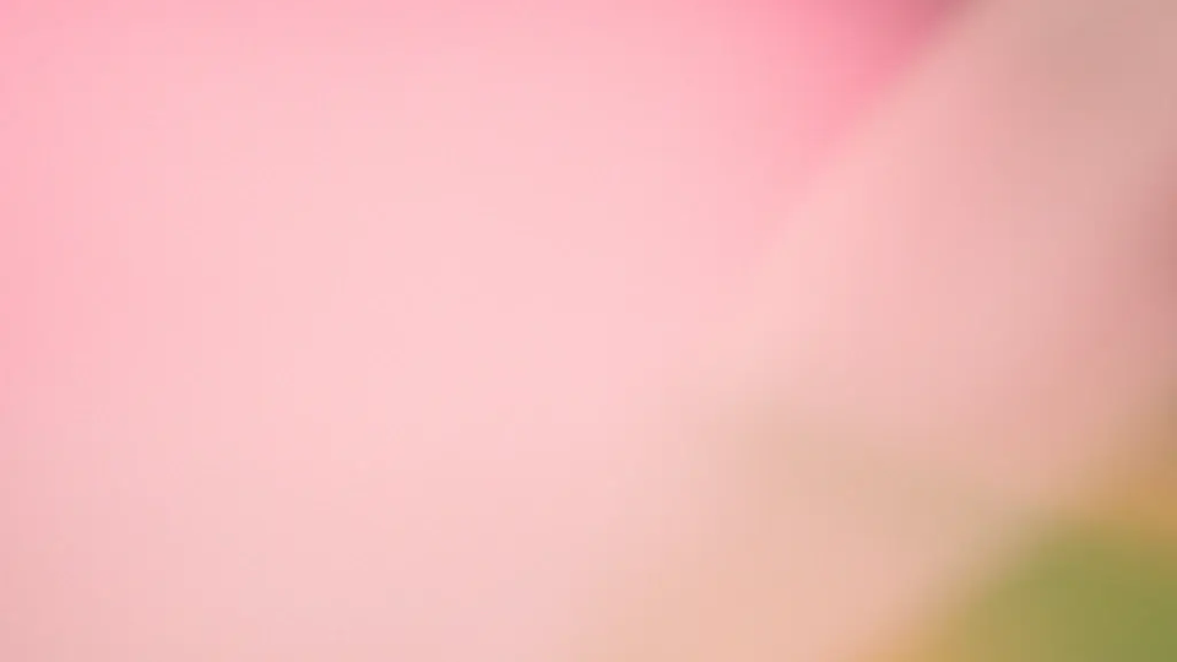 Soft pink and peach gradient background with hints of green, creating an abstract, blurred effect.