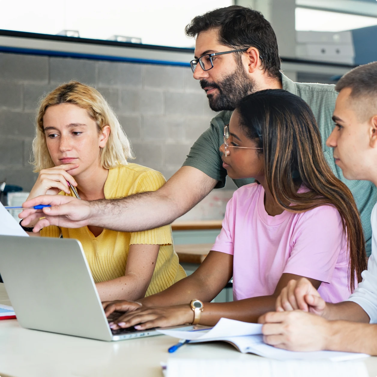 Students and educators gathered around laptops in a classroom.