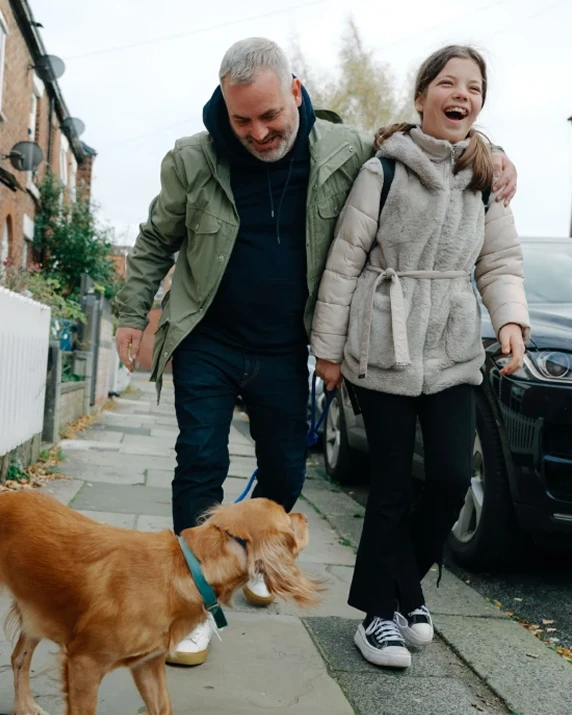 father and daughter walking down the street with dog