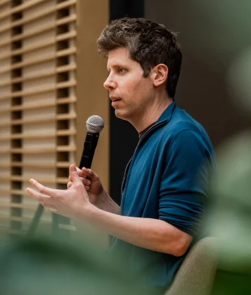 Sam Altman speaking into a microphone during an event.