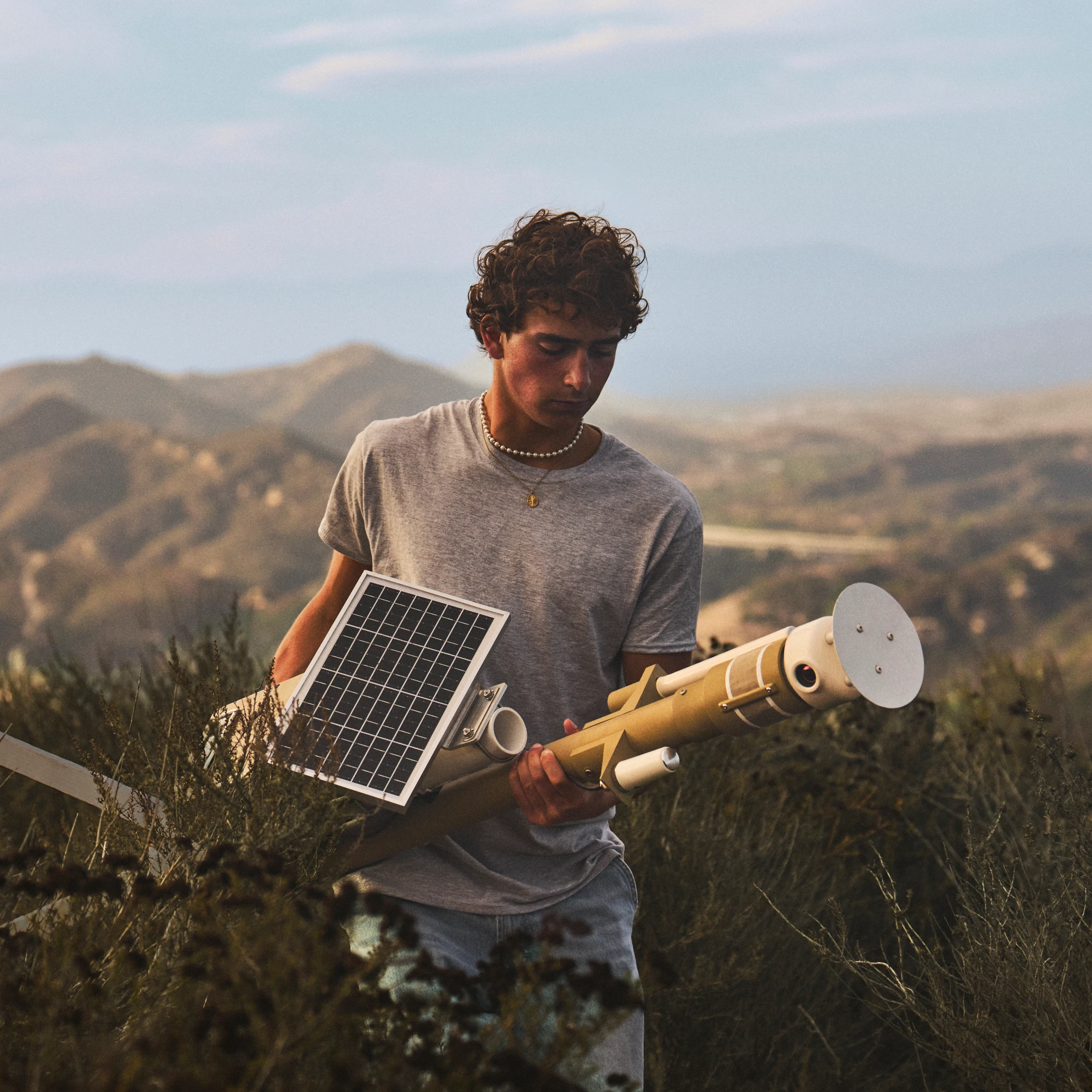 Ryan Honary membawa pengesan kebakaran hutan berkuasa solar merentasi kawasan bukit yang kering.