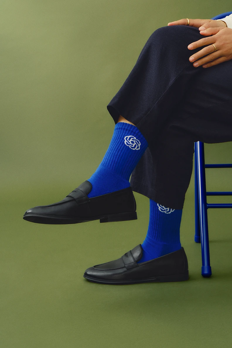 Person wearing blue ChatGPT socks and black loafers while seated