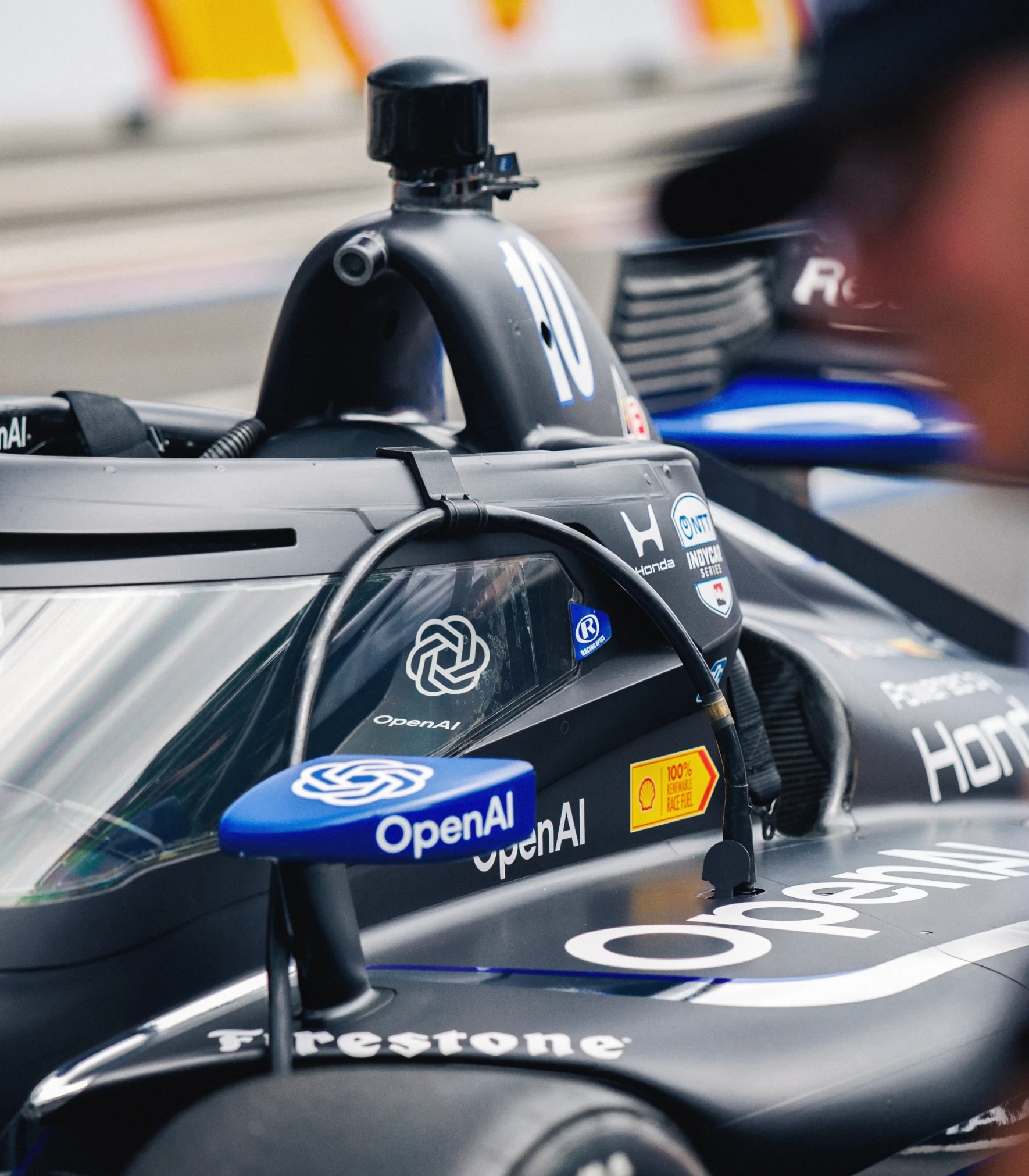 Close-up of the OpenAI-branded number 10 IndyCar’s cockpit in the pit lane.