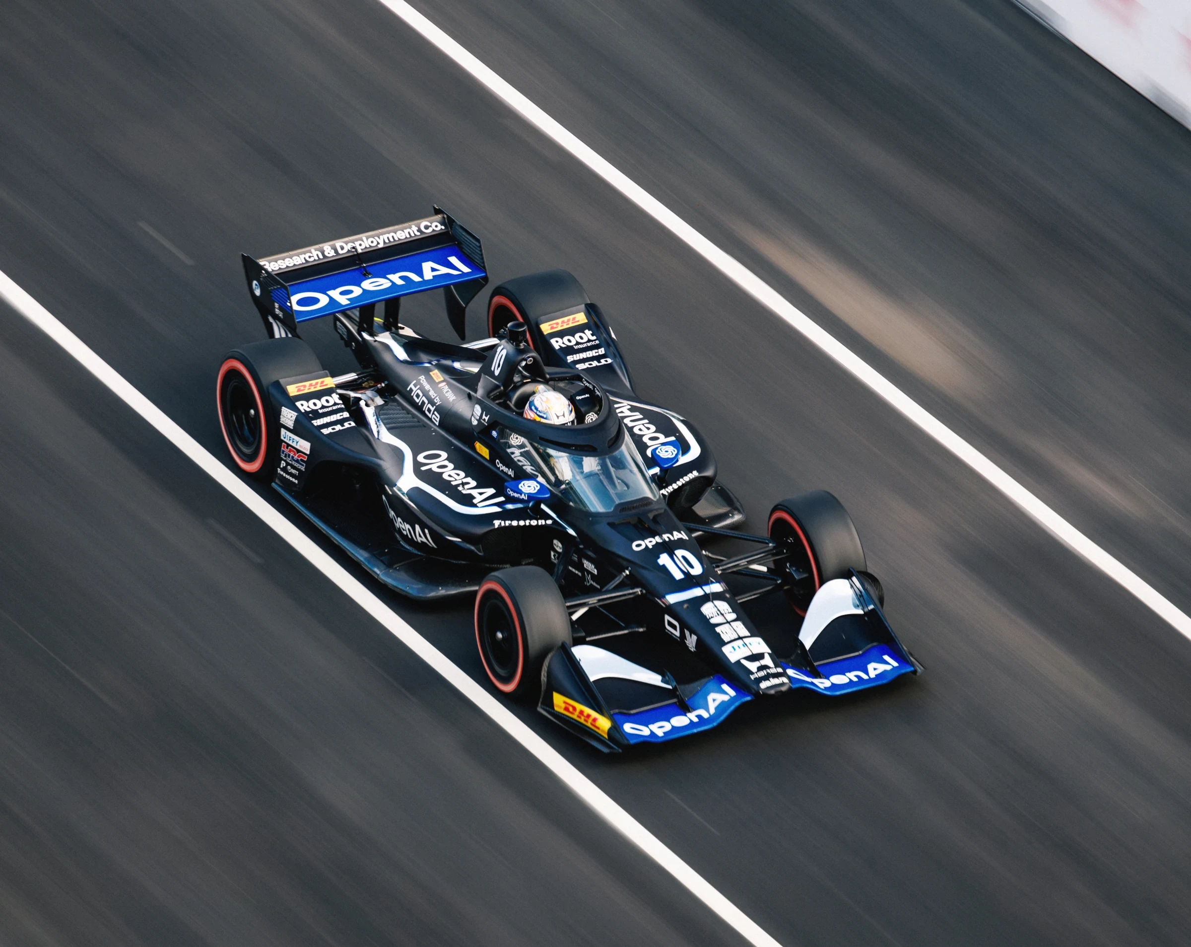 The OpenAI-branded number 10 IndyCar speeds along the track.