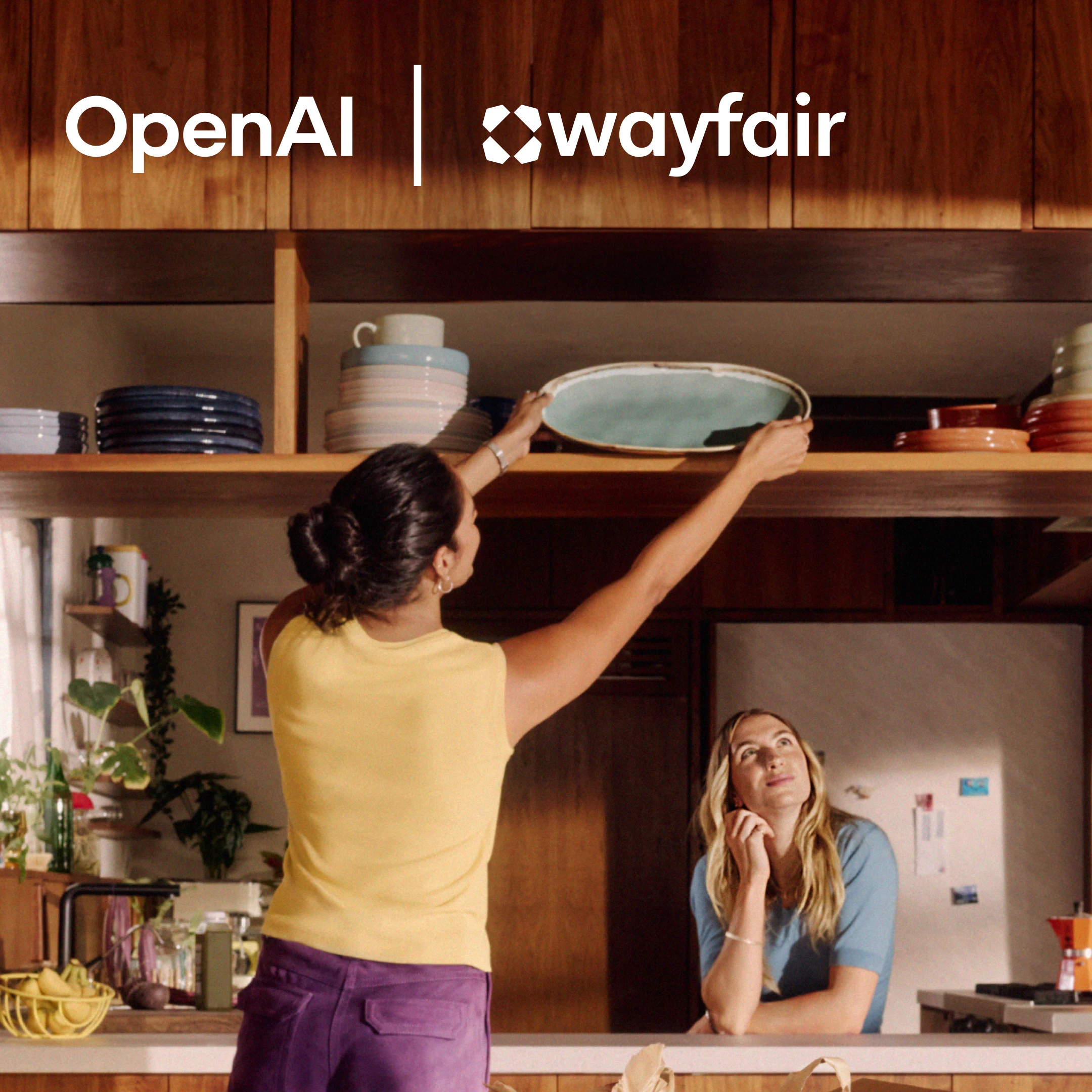 Person placing a serving platter on a kitchen shelf while another watches, with OpenAI and Wayfair logos above.