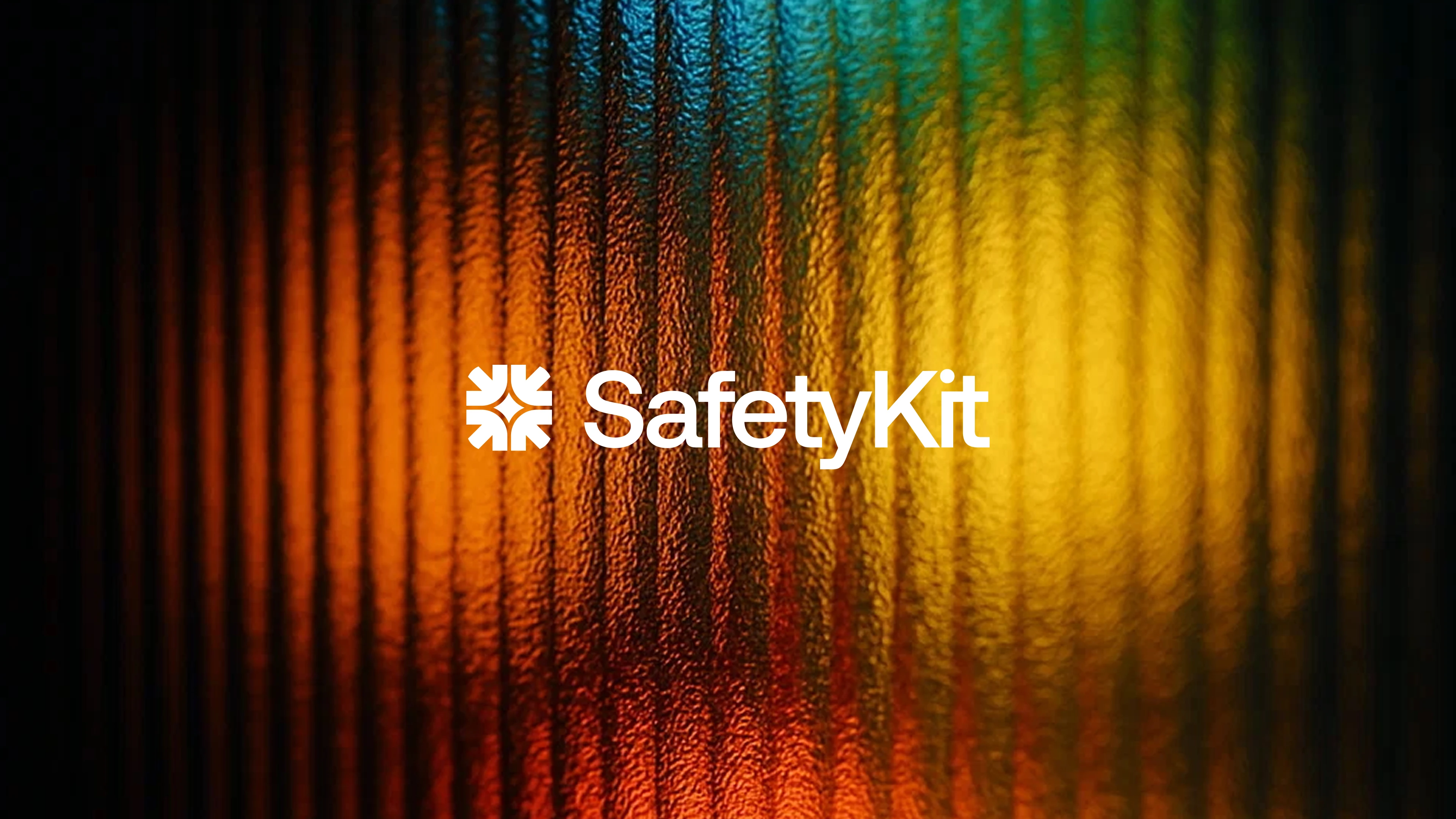 SafetyKit logo in white centered on a dark, vertically textured background with a warm gradient of orange, yellow, and teal light.
