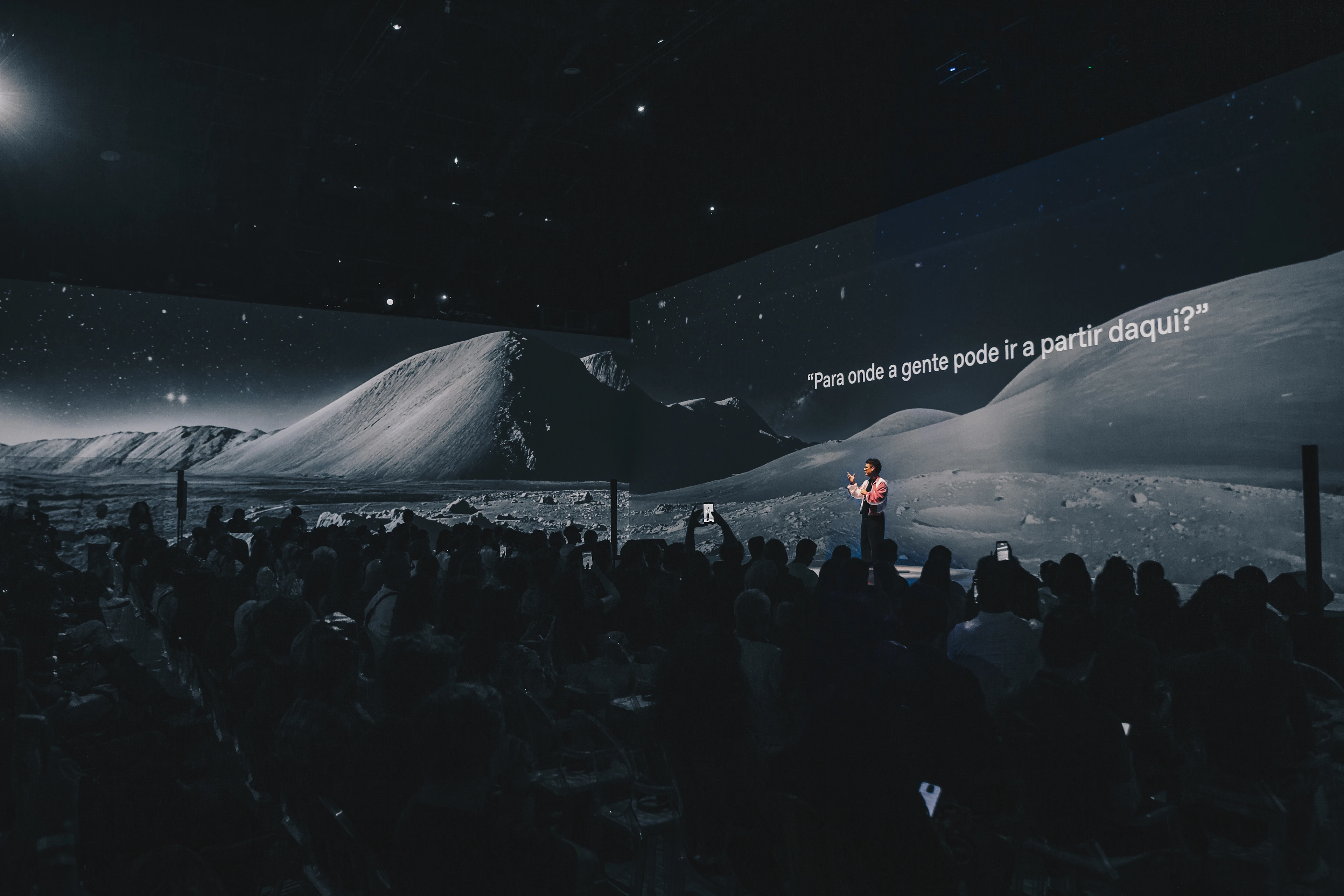 A presenter speaks during OpenAI's Creators Day in Sao Paulo in front of a projected landscape.