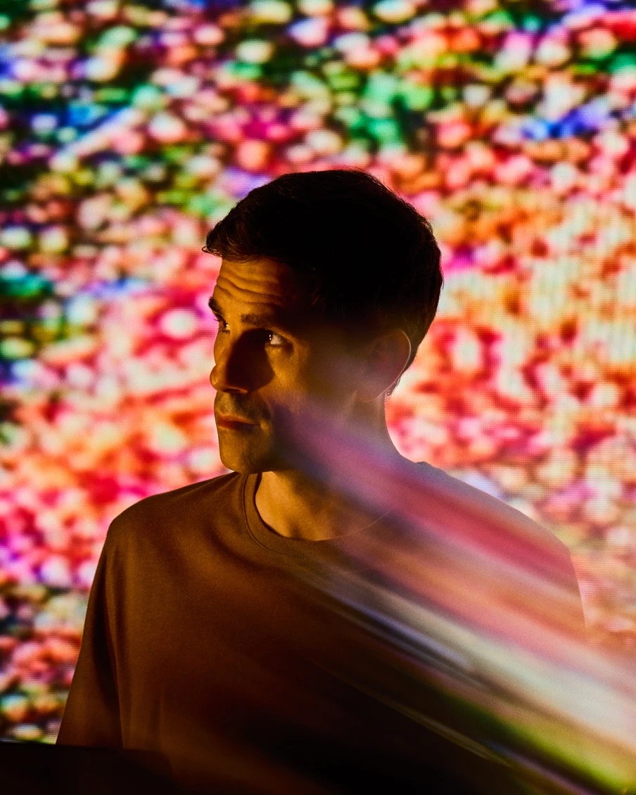 Dr. César de la Fuente in profile against a colorful lab display.