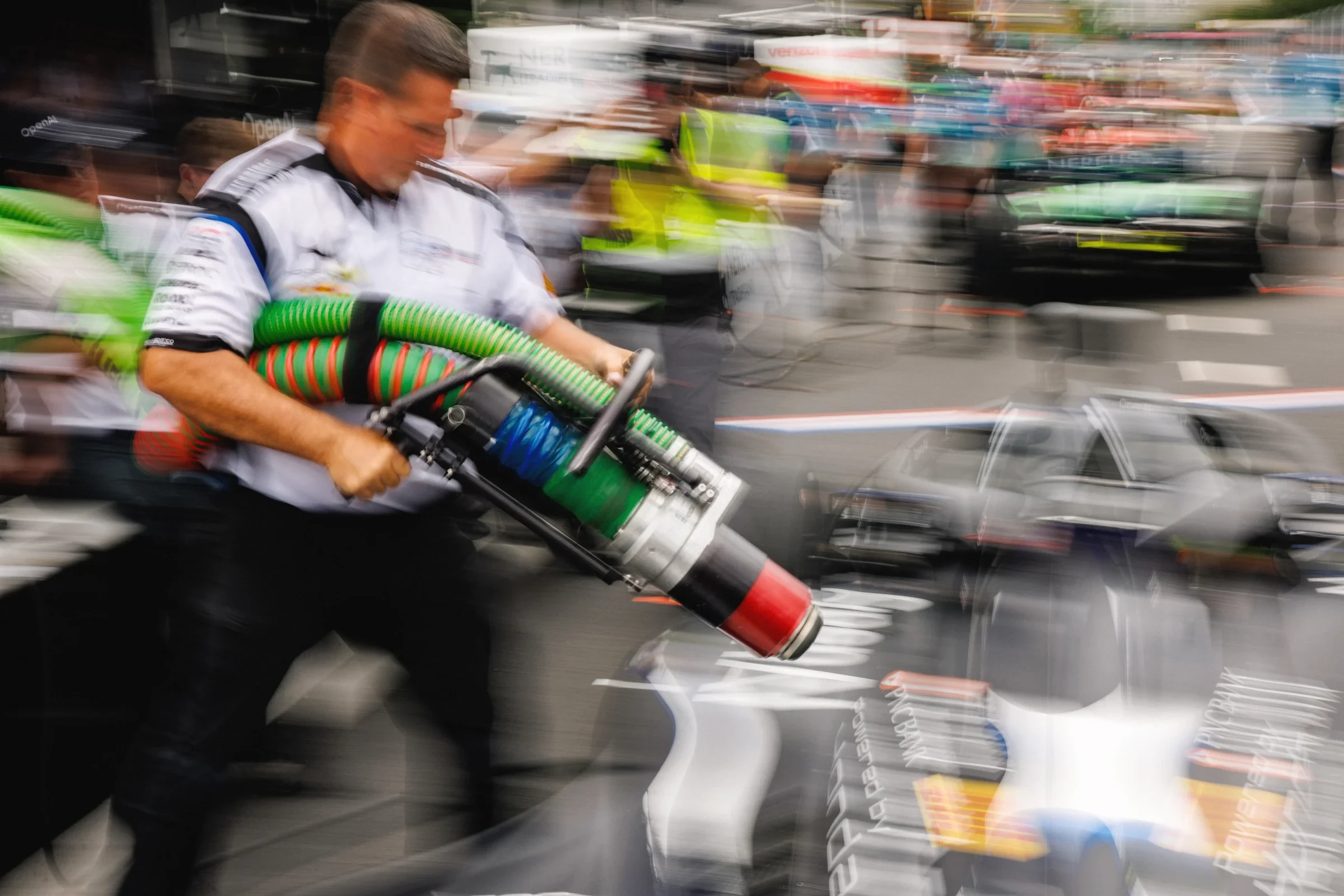 A pit crew member carries equipment through the pit lane.