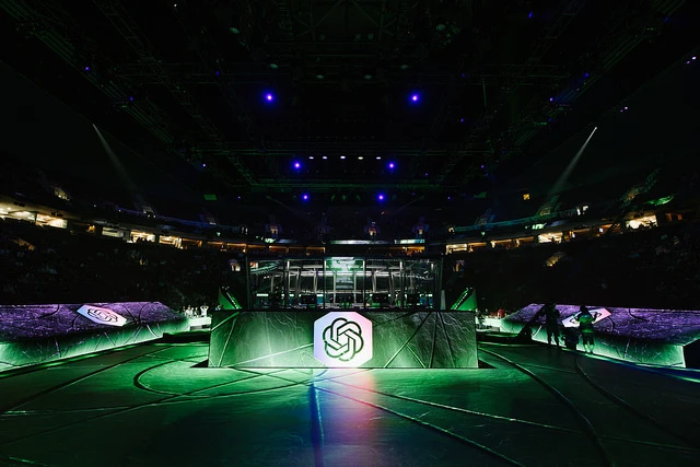 Large, dimly lit Dota 2 competition venue with large OpenAI logo in the center