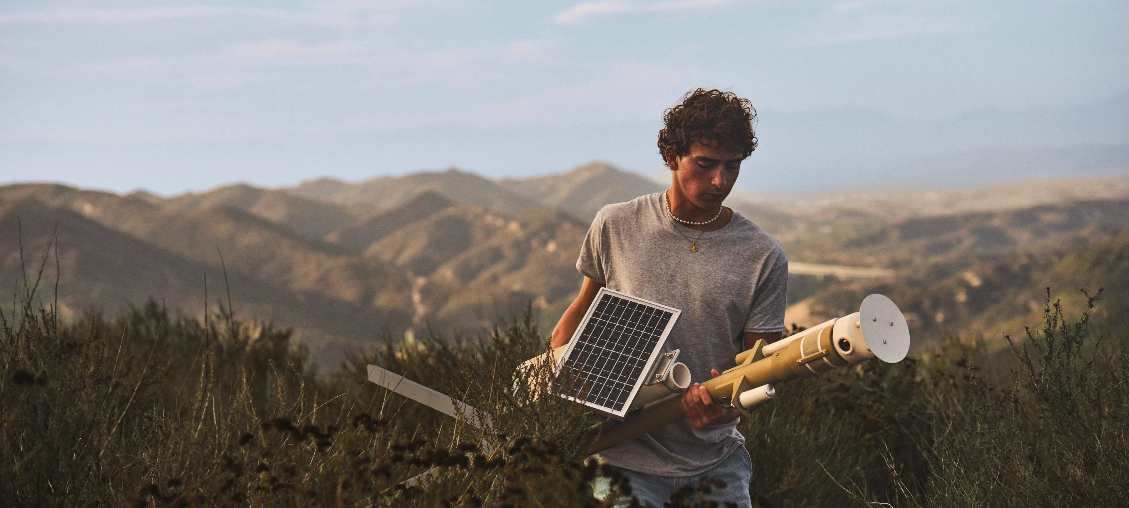 Ryan Honary carries a solar-powered wildfire sensor through dry hills.