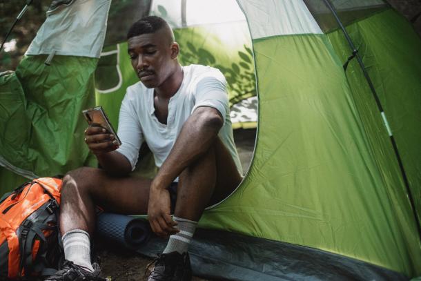 Bestes Outdoor-Handy: Mann mit Handy sitzt im Zelt