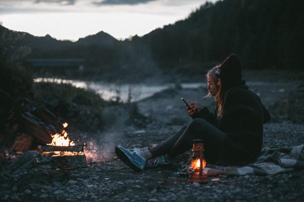 Bestes Outdoor-Handy: Freunde sitzen mit Smartphone am Lagerfeuer