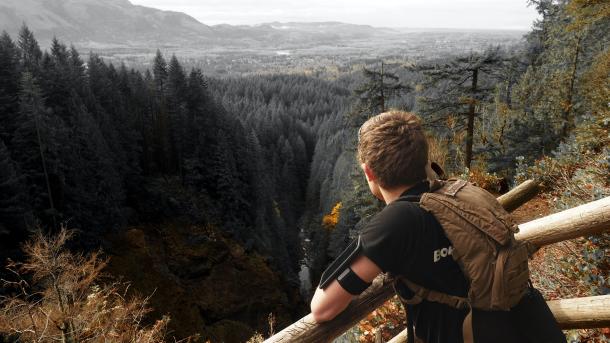 Bestes Outdoor-Handy: Wanderer genießt Aussicht über den Wald und trägt Handy am Arm