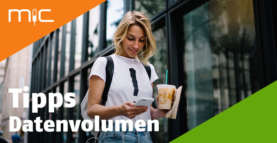 Eine junge Frau schaut unterwegs auf ihr Handy.