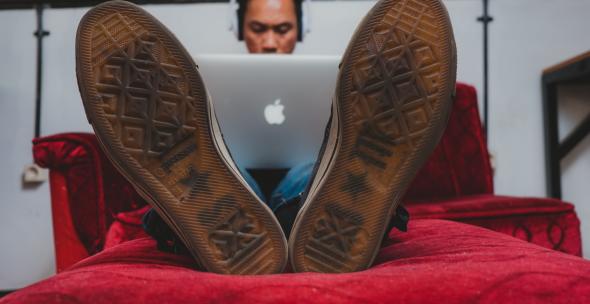 Mann mit MacBook auf Sofa