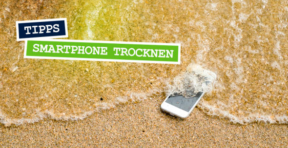 Ein Handy, das am Strand von Wasser umspült ist.