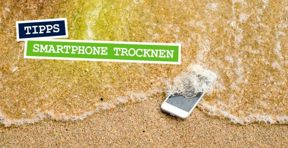 Ein Handy, das am Strand von Wasser umspült ist.