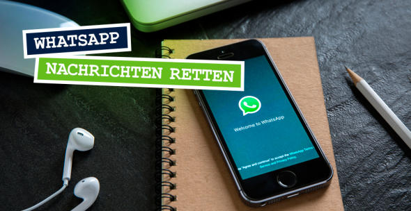 Ein Smartphone auf dem WhatsApp geöffnet ist, liegt auf einem Tisch mit anderen Utensilien.