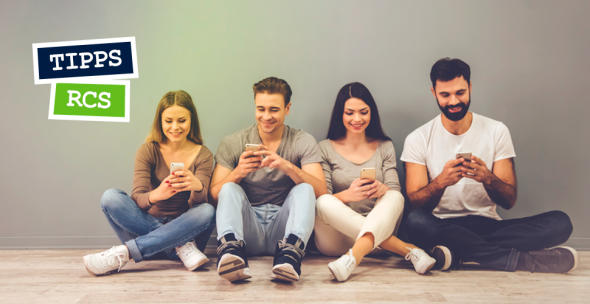 Zwei Männer und Frauen sitzen auf dem Boden mit ihren Smartphones.