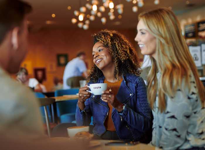 Zwei lachende Frauen im Costa Coffee Shop mit Costa Kaffee
