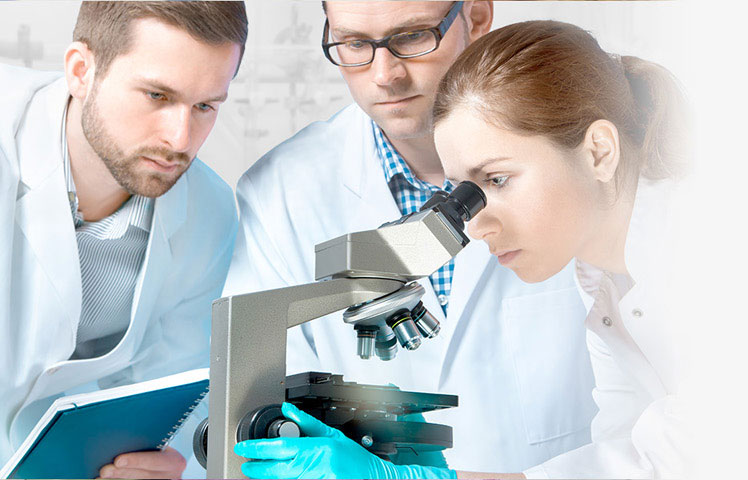 Three healthcare professional in lab coats huddled around a microscope, collaborating on an examination