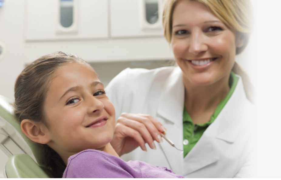 Dentist smiling with girl beside her in a chair