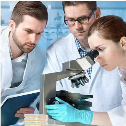 Three healthcare professional in lab coats huddled around a microscope, collaborating on an examination