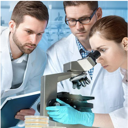 Trois professionnels de la santé en blouse de laboratoire se sont regroupés autour d'un microscope, collaborant à un examen