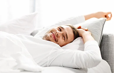 Men stretching in bed after a good night sleep. 