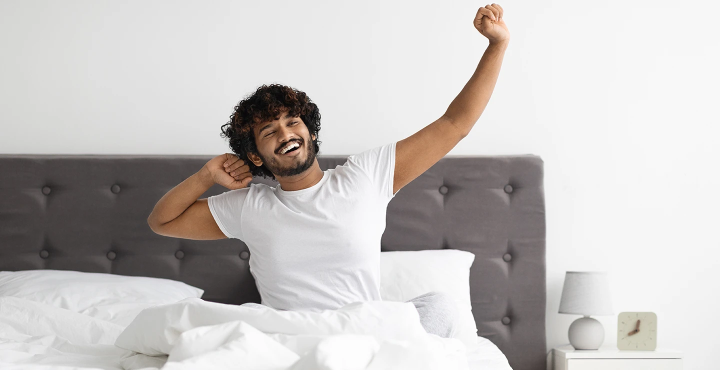 Woman stretching in bed after a good nigh sleep after taking melatonin supplement. 