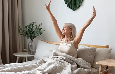 Woman stretching in bed after a good nigh sleep after taking melatonin supplement. 