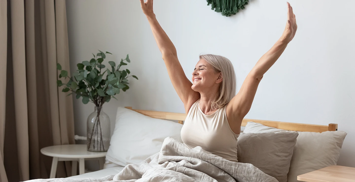 Woman stretching in bed after a good nigh sleep after taking melatonin supplement. 