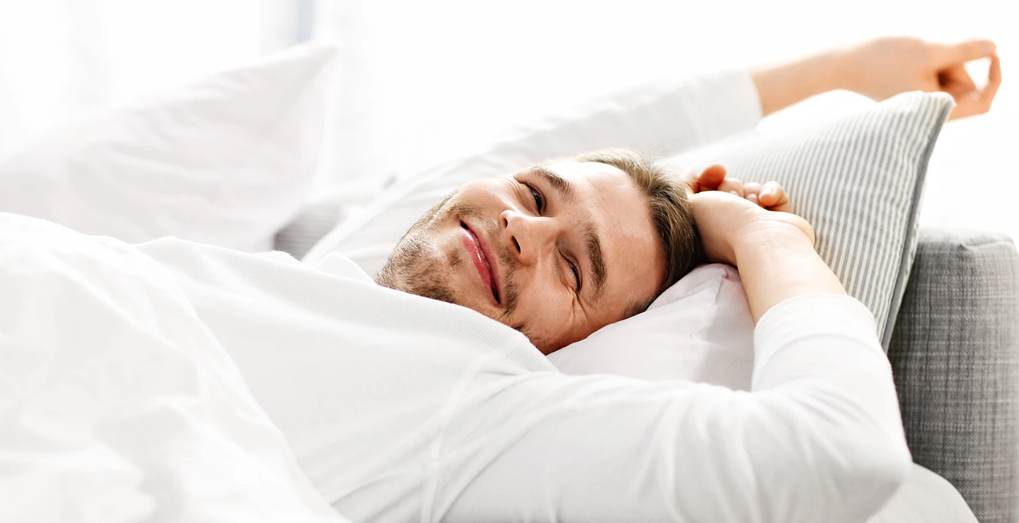 Men stretching in bed after a good night sleep. 