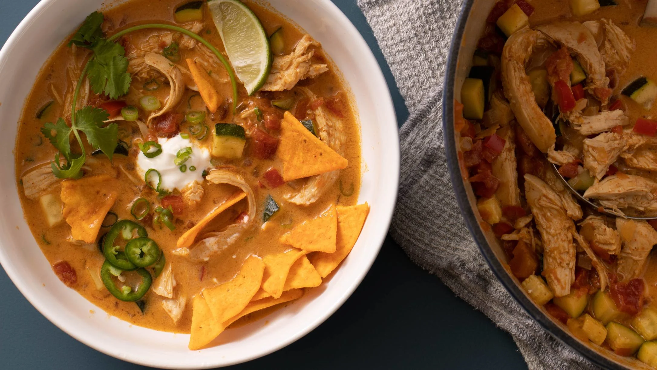 Chicken taco soup with sour cream, lime, jalapeños and crispy tortilla chips, served alongside a chicken vegetable stew.