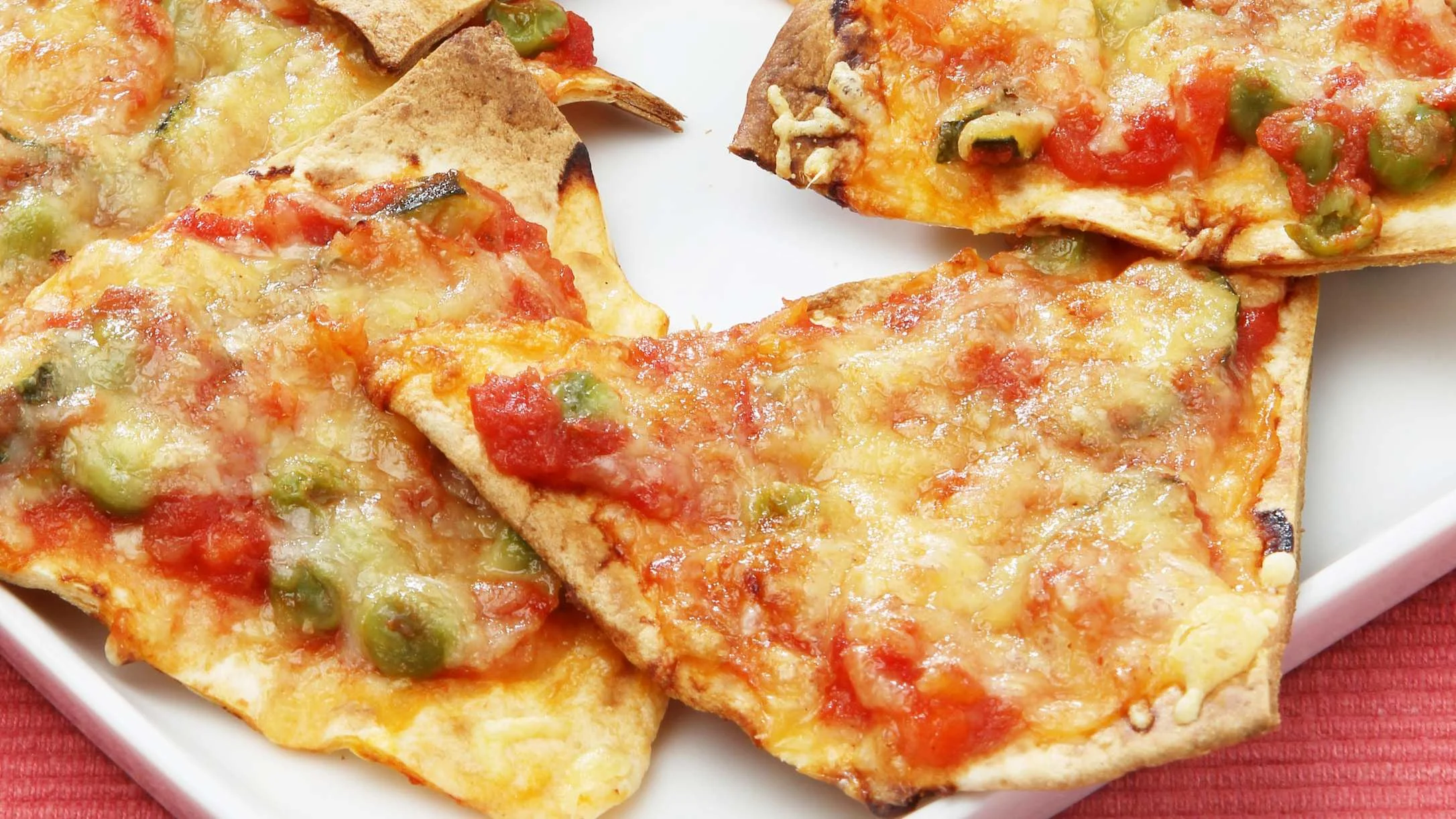 Homemade flatbread pizza slices topped with melted cheese, salsa, and green chilies on a white plate.
