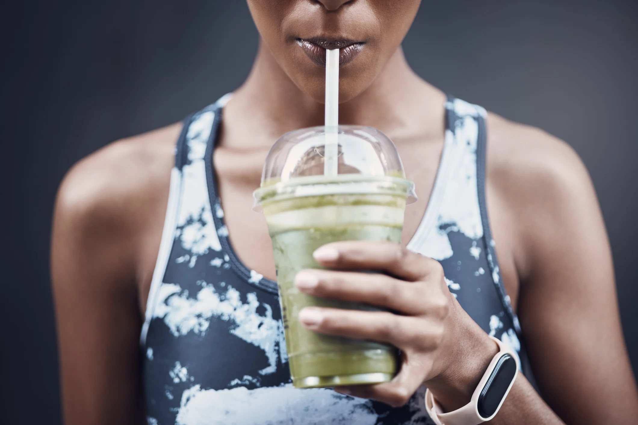 Woman in sport clothes drinking a green smoothie