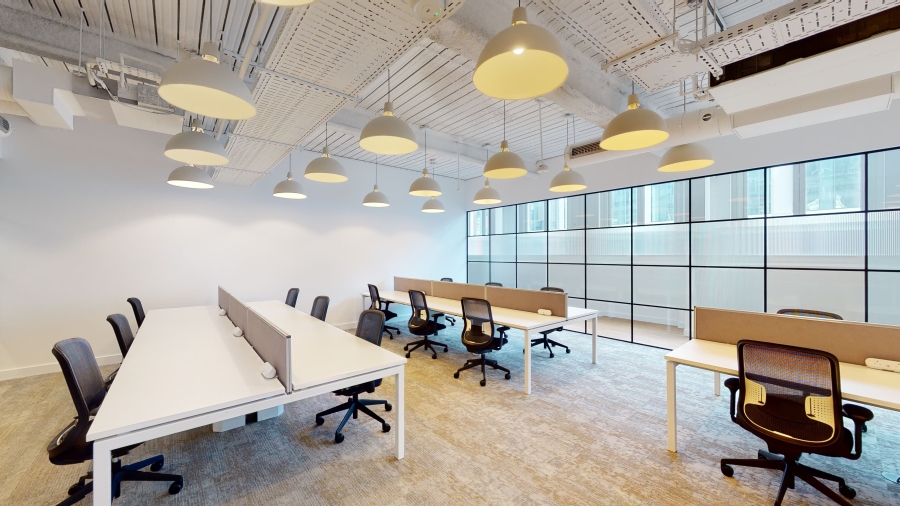 Interior of an office with multiple desks, office chairs and pendant ceiling lights