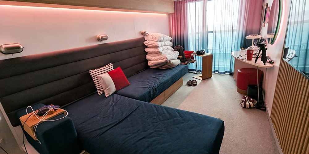 My Cabin on a Virgin Voyages Cruise, showing my Seabed converted to couch mode ... and also all my stuff everywhere. 
