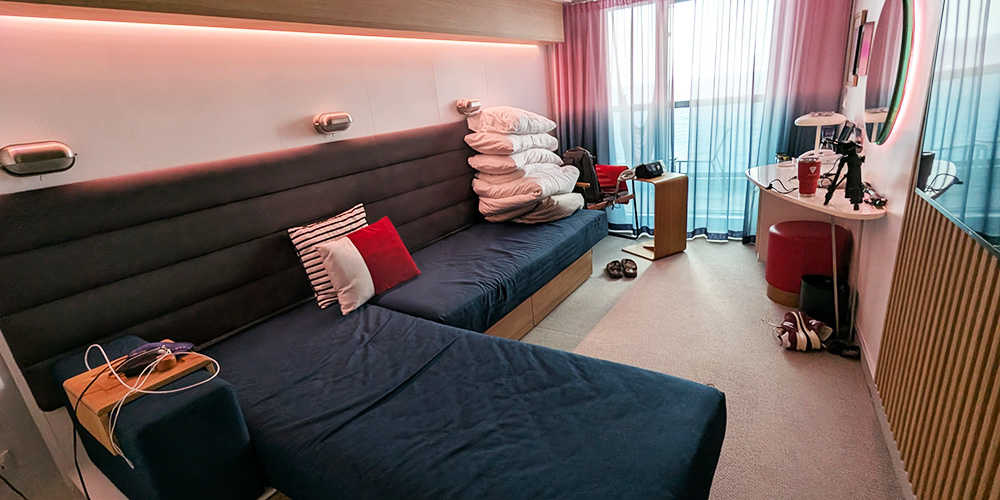 My Cabin on a Virgin Voyages Cruise, showing my Seabed converted to couch mode ... and also all my stuff everywhere.