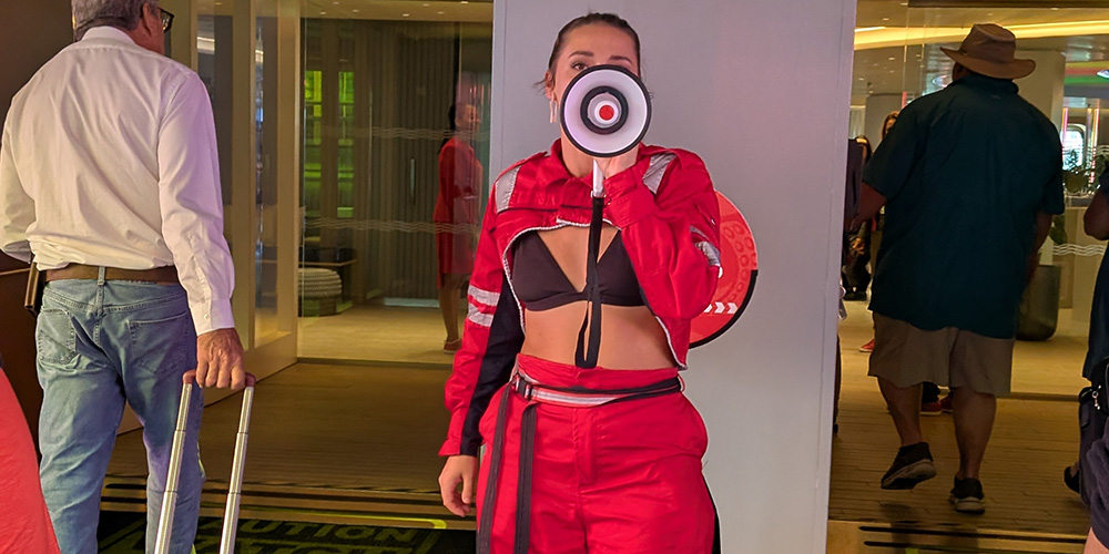 A Virgin Voyages crew member welcoming guests onbaord.