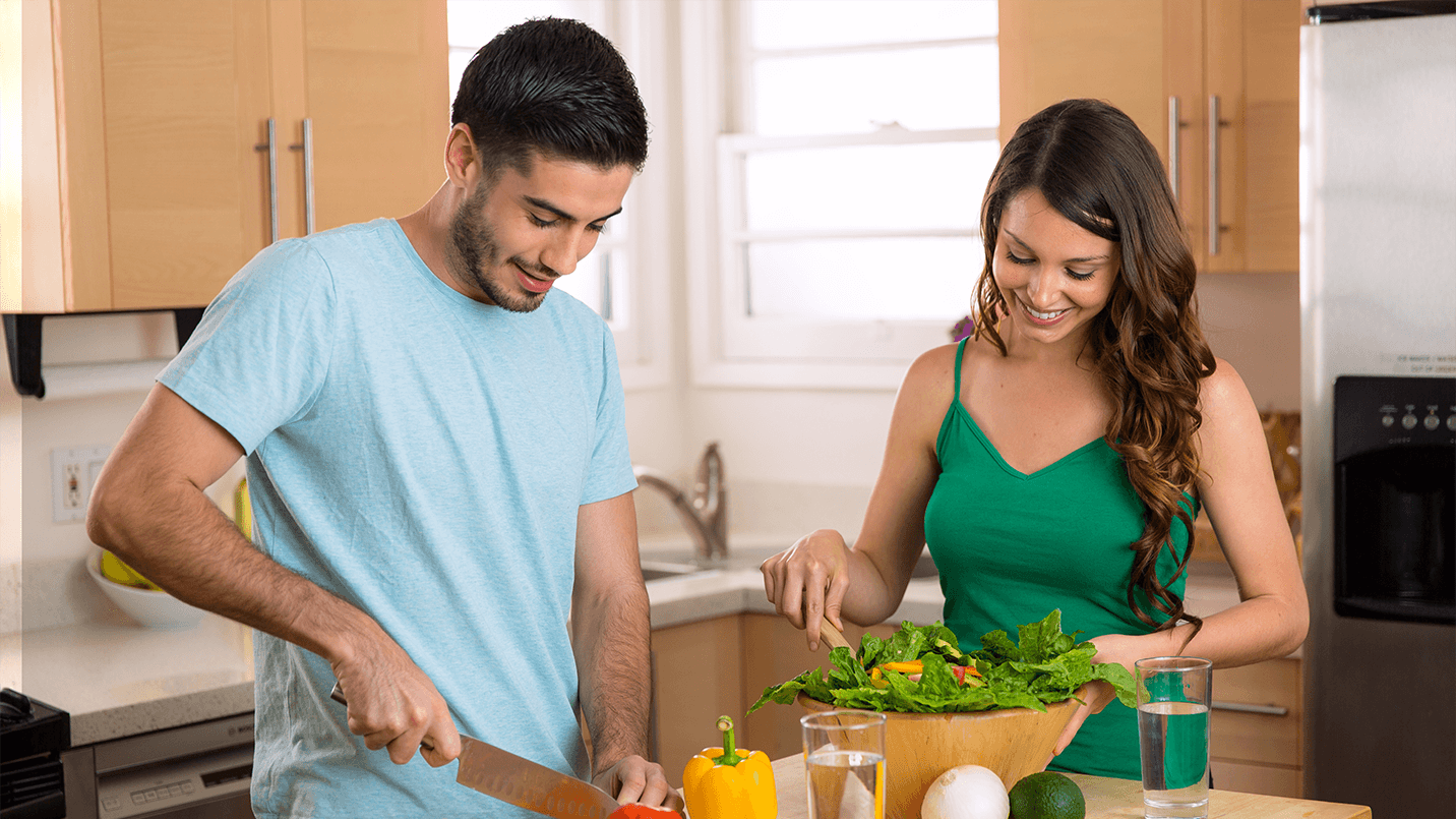 male and female cooking a healthy dinner together in their kitchen