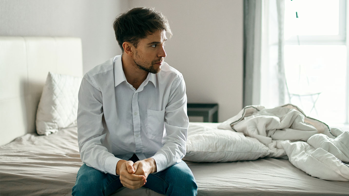 Nervous man sitting on bed