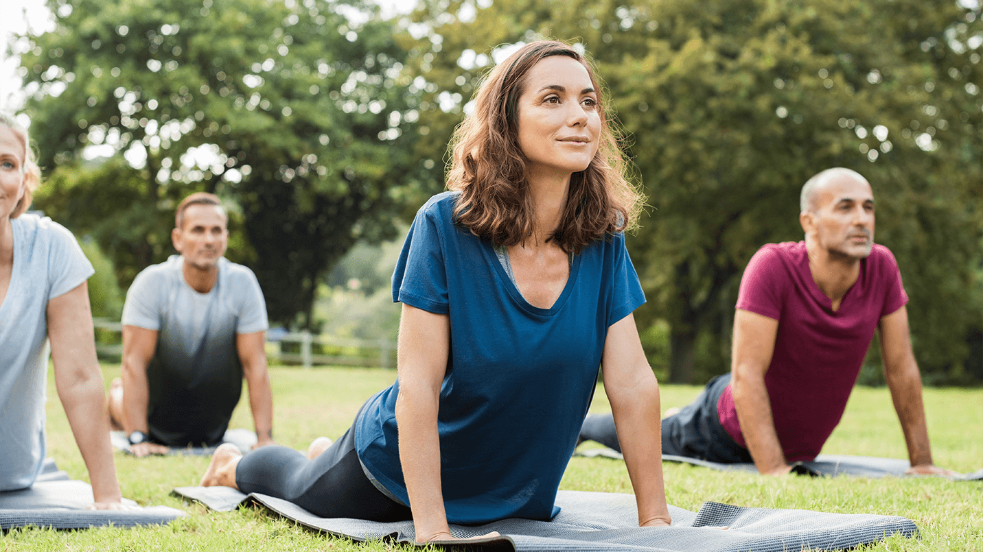 two women and two men doing yoga in the park