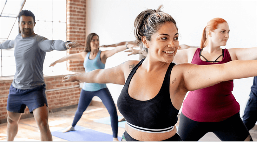 A workout class of a diverse group of people doing a spread arm stretch