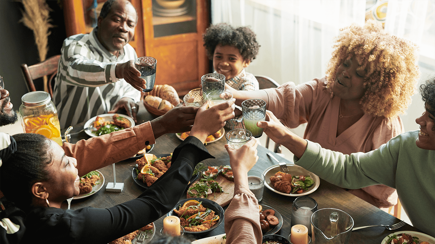 African American family eating a holiday meal and toasting their glasses